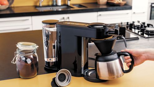 Cafetera Philips Senseo Switch negra sobre una encimera, con una persona sujetando la jarra térmica.