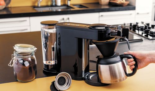 Cafetera Philips Senseo Switch negra sobre una encimera, con una persona sujetando la jarra térmica.