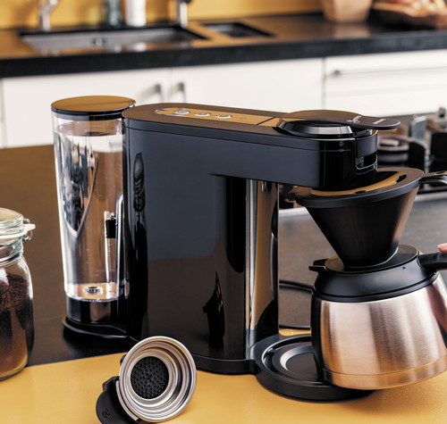 Cafetera Philips Senseo Switch negra sobre una encimera, con una persona sujetando la jarra térmica.