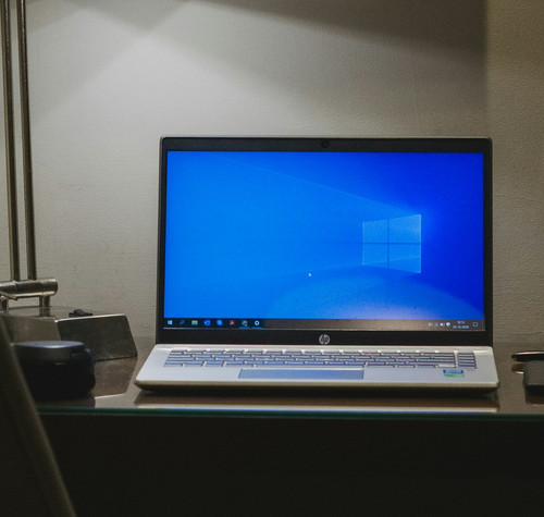 Portátil HP abierto sobre un escritorio, con Windows en pantalla y una lámpara a su lado.