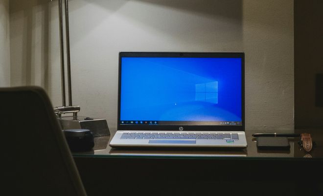 Portátil HP abierto sobre un escritorio, con Windows en pantalla y una lámpara a su lado.