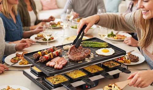 Parrilla raclette sobre una mesa con verduras, carne y pequeñas bandejas para fundir queso durante una cena.