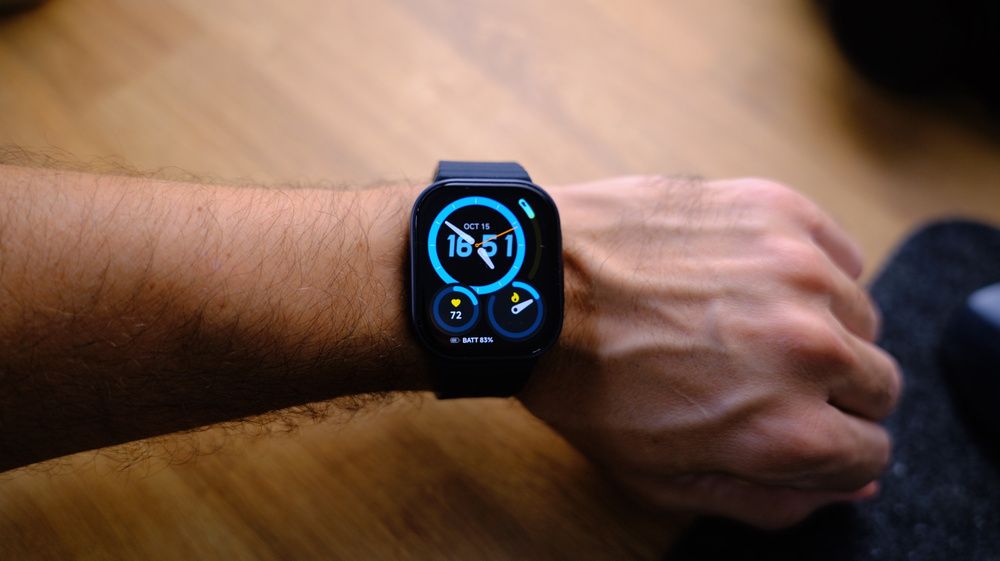 Primer plano de un reloj inteligente con correa negra y una esfera digital con indicadores circulares de colores.
