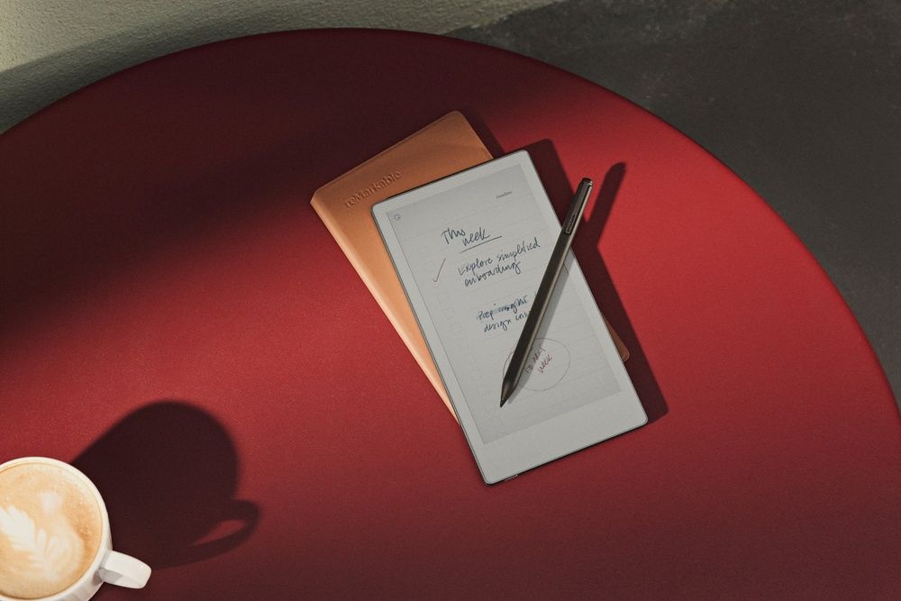 reMarkable Paper Pro Move con Marker y funda sobre una mesa junto a una taza de café.