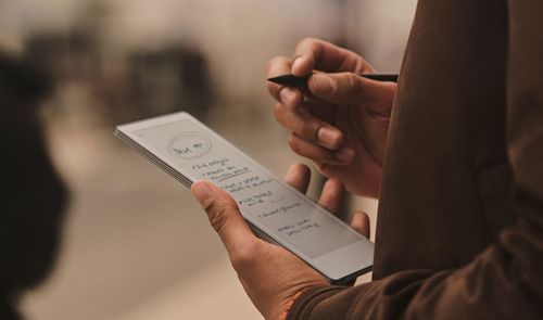 Una persona sostiene un reMarkable Paper Pro Move con notas manuscritas y un lápiz digital en la otra mano.