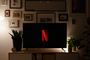 Televisor con el logotipo de Netflix sobre un mueble, en un salón con iluminación cálida.