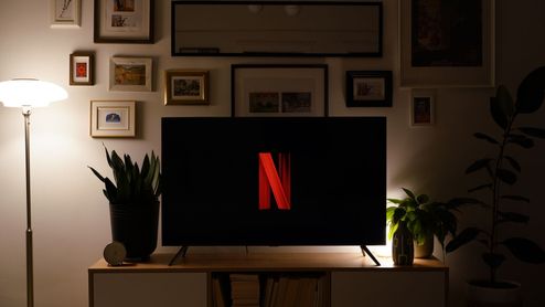 Televisor con el logotipo de Netflix sobre un mueble, en un salón con iluminación cálida.