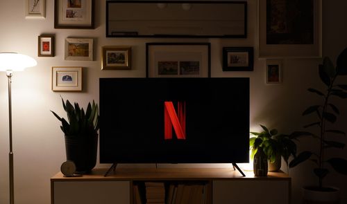 Televisor con el logotipo de Netflix sobre un mueble, en un salón con iluminación cálida.