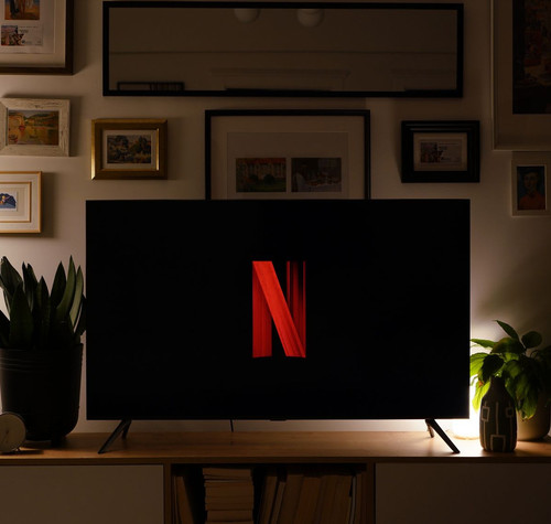 Televisor con el logotipo de Netflix sobre un mueble, en un salón con iluminación cálida.