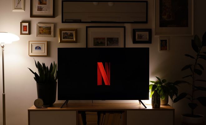Televisor con el logotipo de Netflix sobre un mueble, en un salón con iluminación cálida.