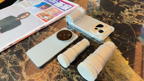 Vivo X500 Pro Max junto a dos objetivos externos y una funda con empuñadura sobre una mesa de mármol.