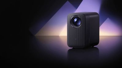 Proyector Xiaomi Smart Projector L1 Pro negro sobre una superficie reflectante, con iluminación violeta de fondo.