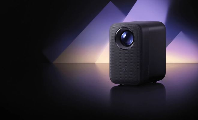 Proyector Xiaomi Smart Projector L1 Pro negro sobre una superficie reflectante, con iluminación violeta de fondo.