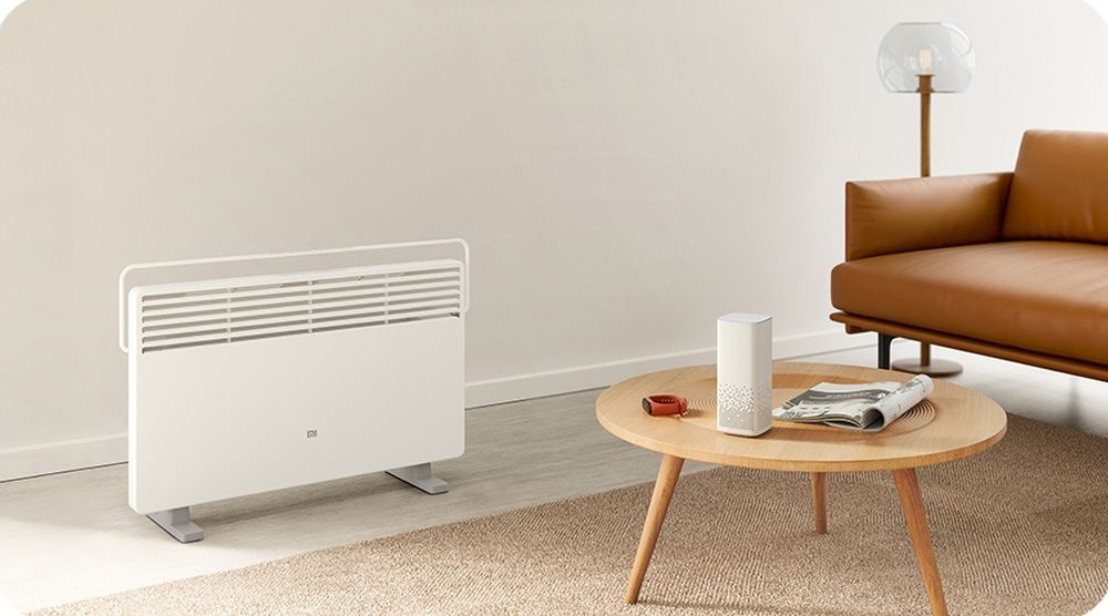 Xiaomi Mi Smart Space Heater S junto a una mesa redonda y un sofá de cuero marrón.