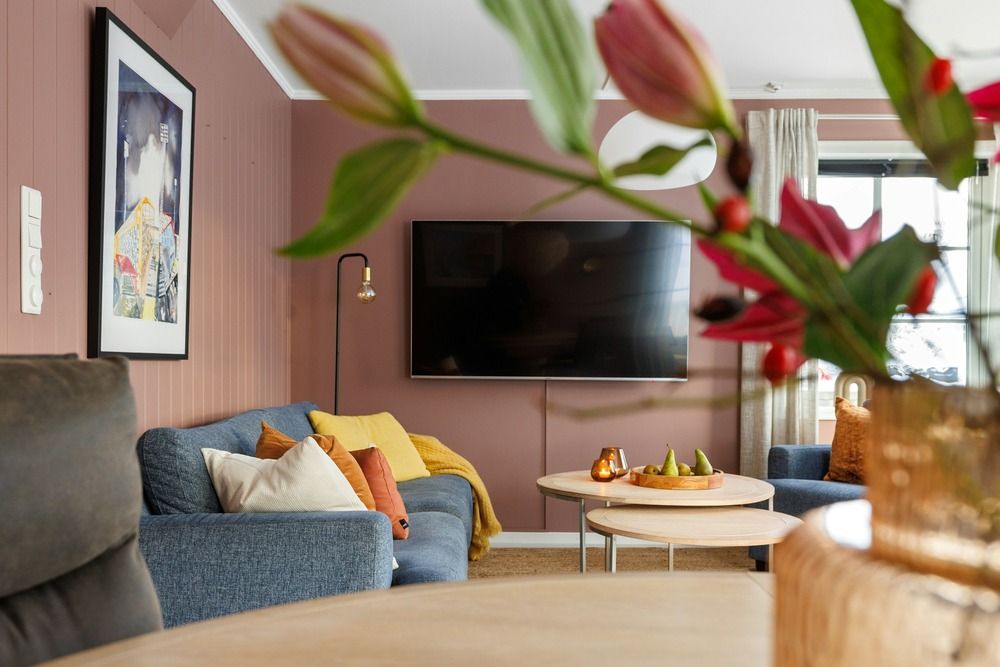 Televisor de pantalla plana en un salón moderno con sofá y decoración cálida.